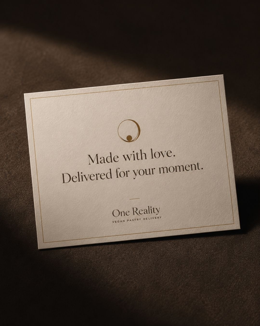 One Reality vegan pastry delivery thank-you card on a brown velvet surface with gold foil typography